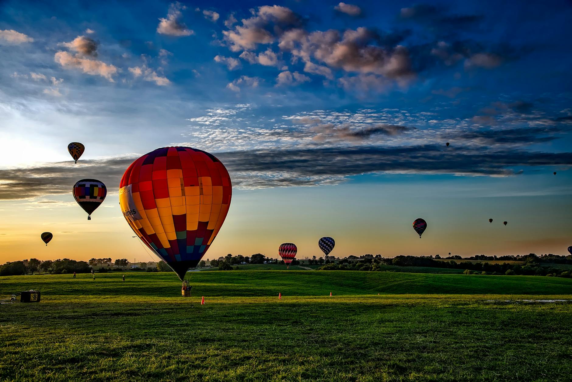 assorted color hot air balloons on grass field during golden hour